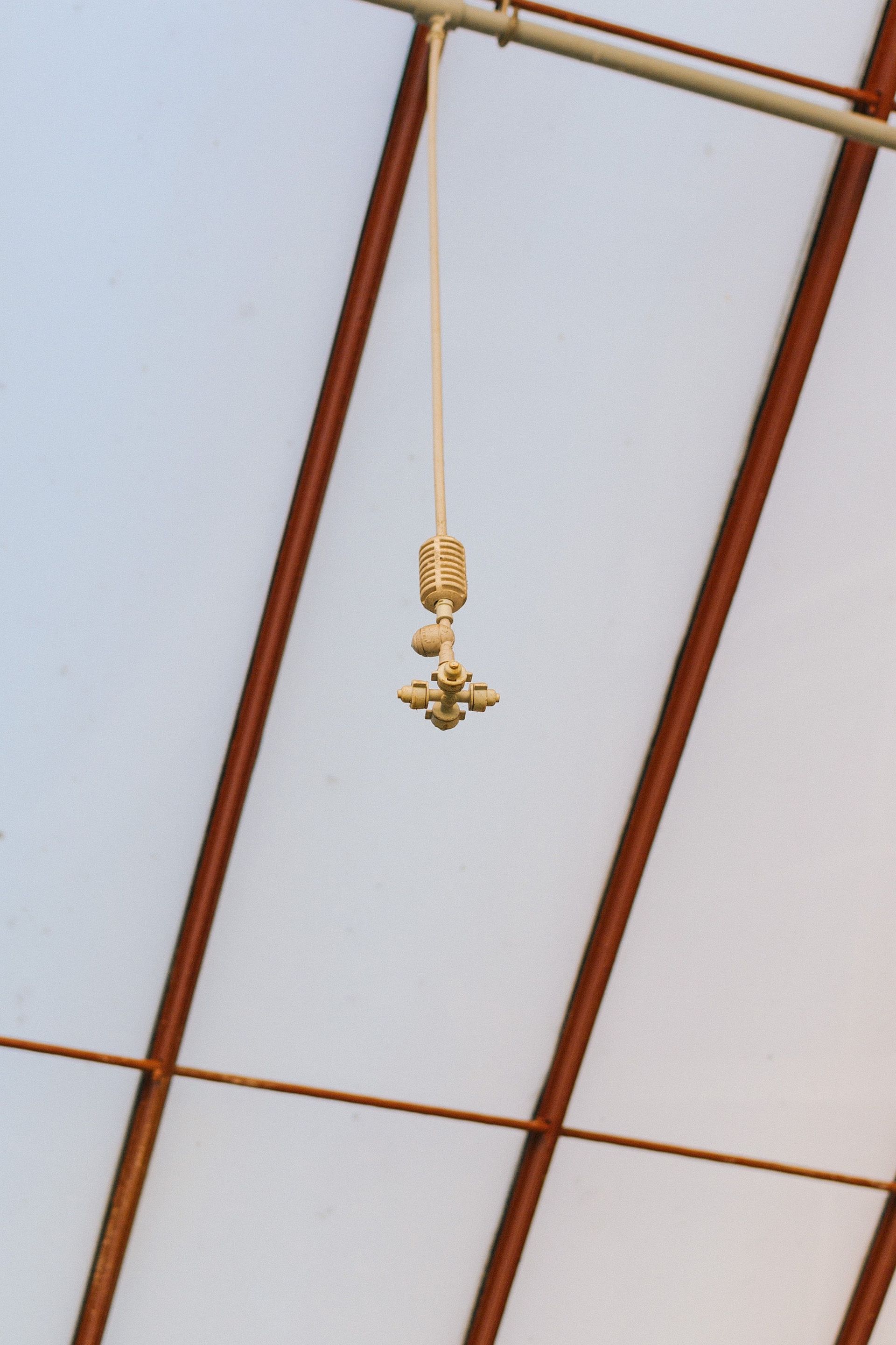 Close-up of an industrial water sprinkler system hanging inside a greenhouse.